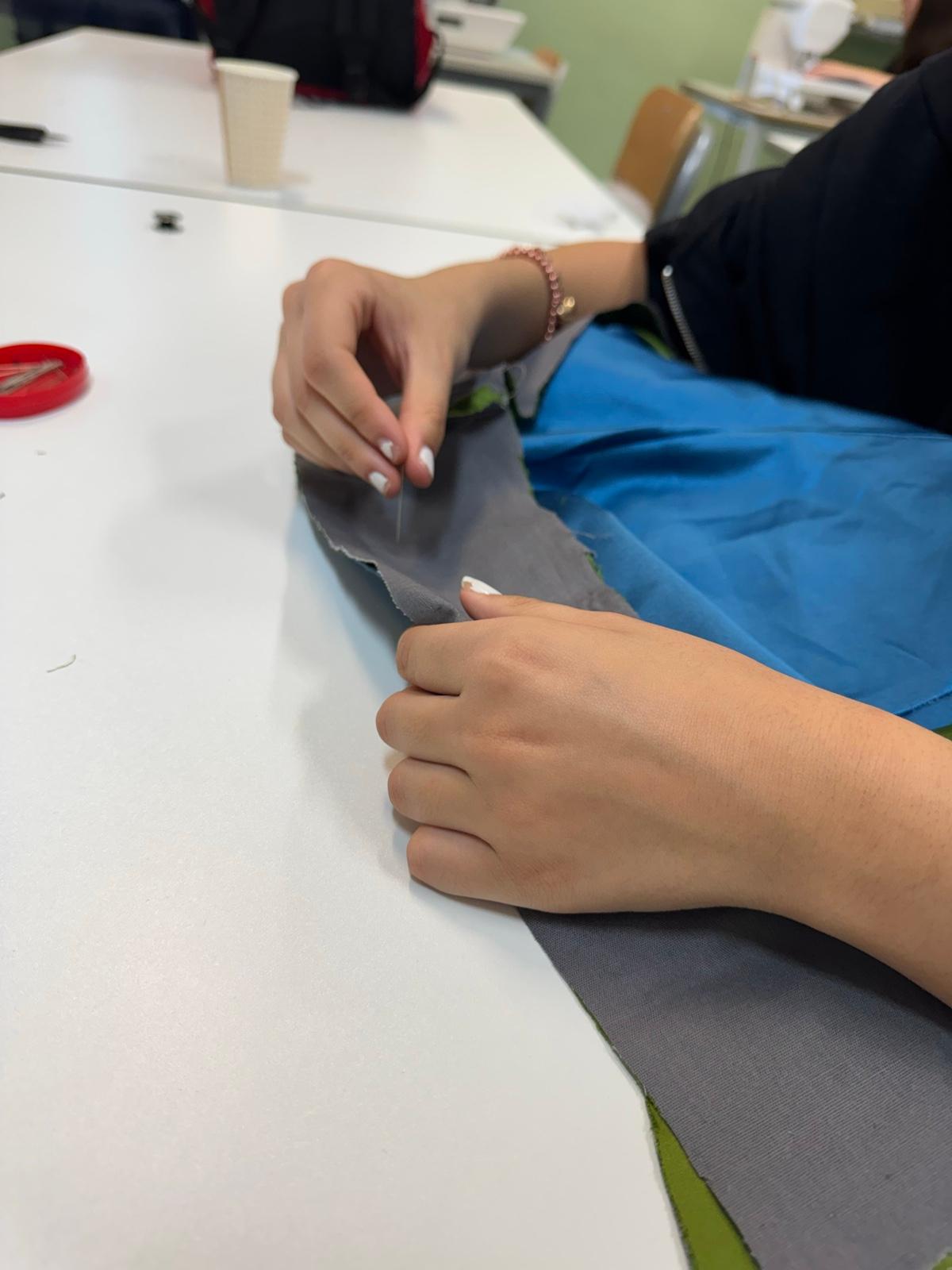 Cucitura manuale su tessuto durante il lavoro in laboratorio